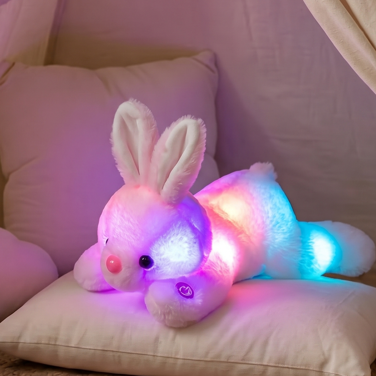 Light-up plush bunny toy on a pillow inside a children's play tent with books on the floor.